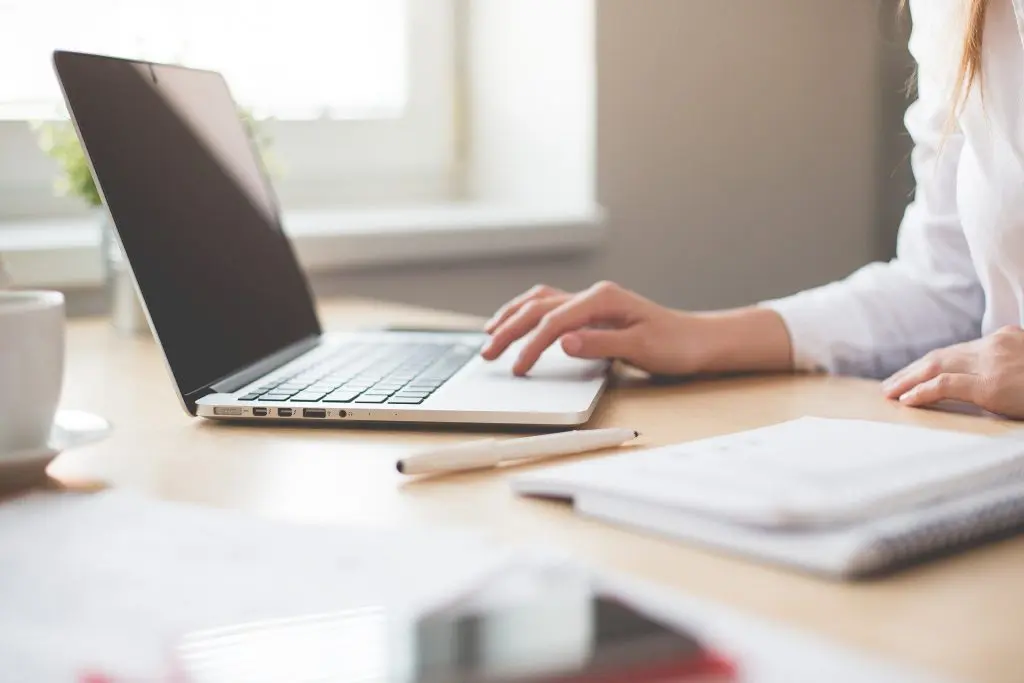 woman sitting at table while working on her laptop