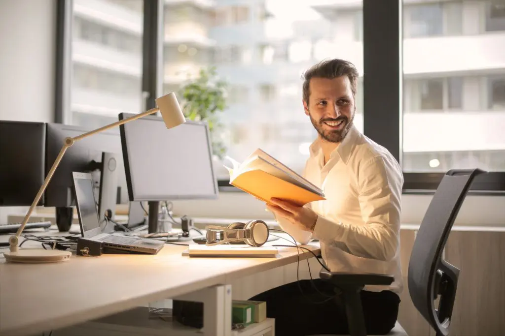 happy man holding a book in a private office space