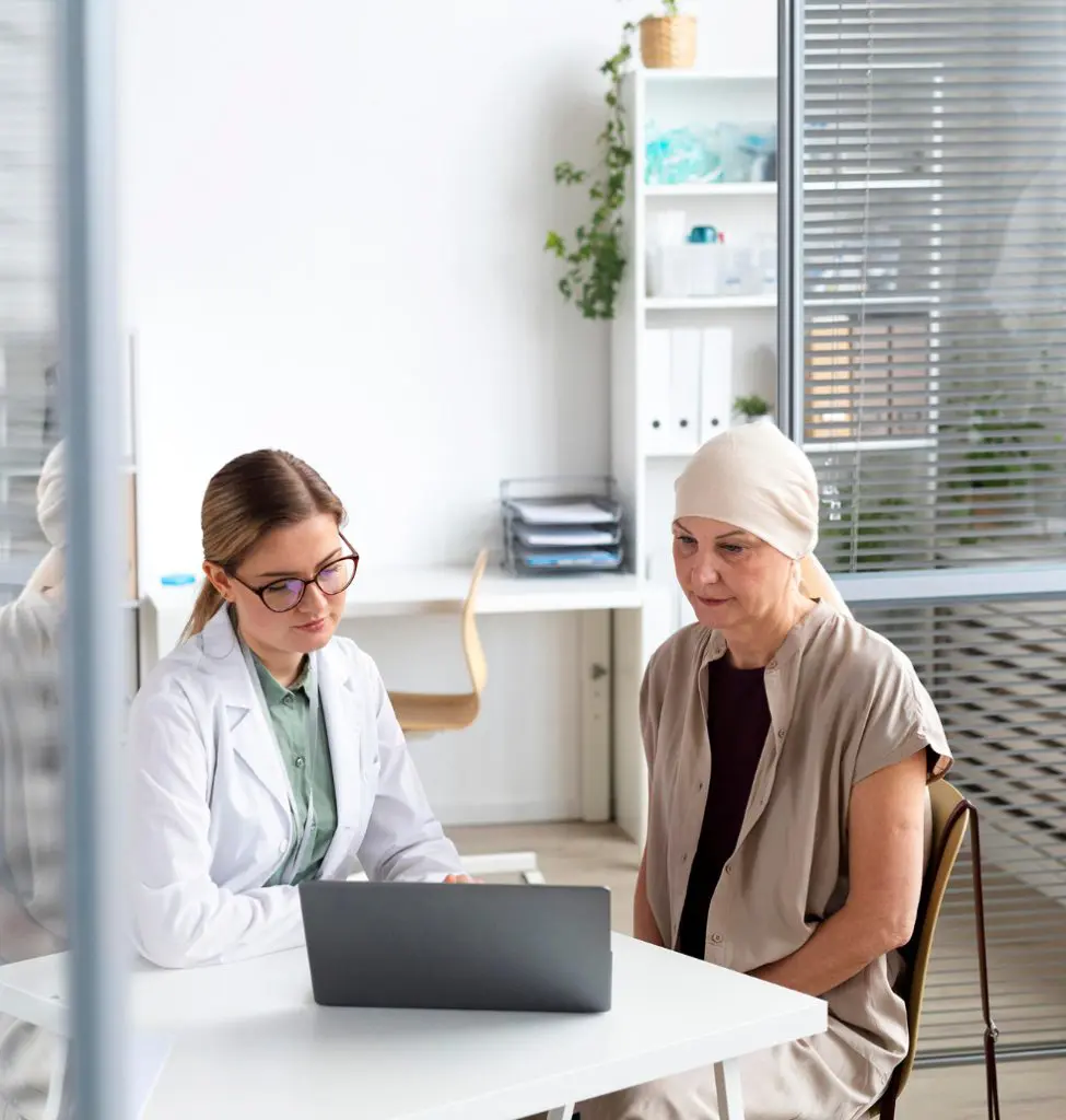 Barrister Suites Office Lease A doctor in a white coat sits at a desk with a laptop, consulting with a woman wearing a headscarf, in a bright medical office. The atmosphere appears professional and supportive.