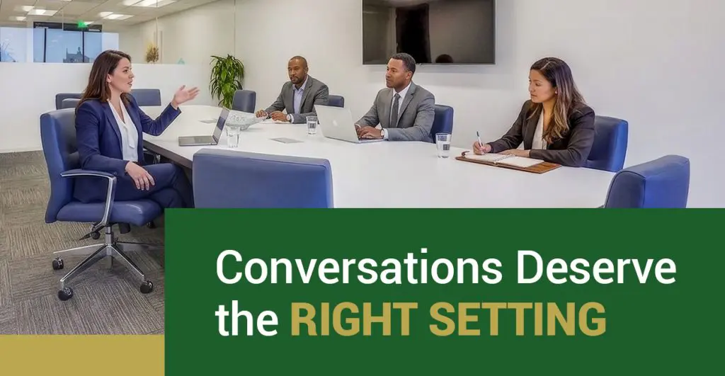 Barrister Suites Office Lease Four people in business attire sit around a conference table in a modern office, two with laptops and one taking notes, with text overlay: “Conversations Deserve the RIGHT SETTING.”.