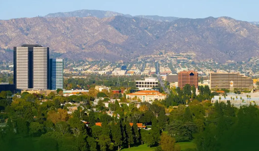 Barrister Suites Office Lease Cityscape with tall office buildings, residential areas, and abundant trees in the foreground, set against a backdrop of mountains under a clear sky.