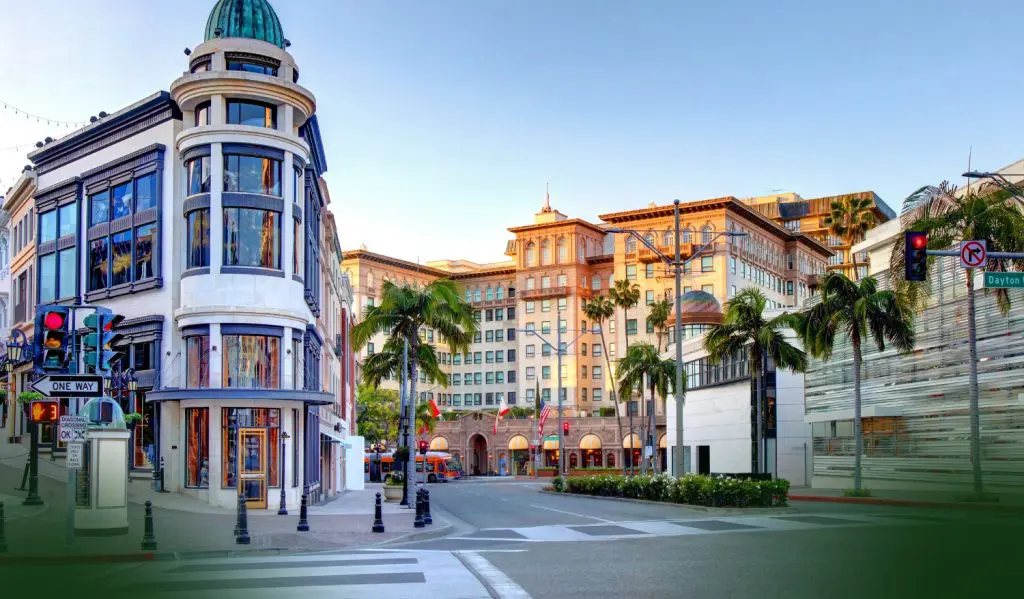 Barrister Suites Office Lease A sunny intersection in Beverly Hills, Los Angeles, featuring palm trees, luxury shops, historic buildings, and a clear blue sky. The street signs read “Dayton Way” and “Rodeo Dr.”.