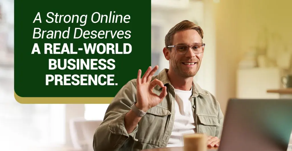 Barrister Suites Office Lease A man wearing glasses sits at a table with a laptop, smiling and making an “OK” gesture. Text on the image reads: A Strong Online Brand Deserves A Real-World Business Presence.