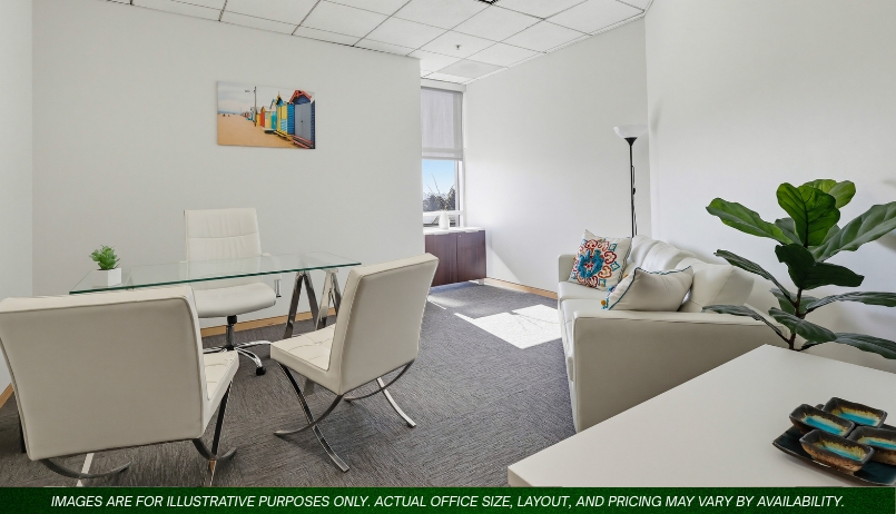 Barrister Suites Office Lease A modern office with white walls, a glass desk, white chairs, a white sofa with colorful pillows, a standing lamp, a green plant, and a window letting in natural light. A beach-themed painting hangs on the wall.