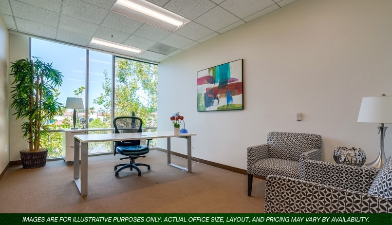 Barrister Suites Office Lease Modern office with large window, white desk, black office chair, patterned armchairs, a table lamp, and colorful abstract art on the wall. Natural light fills the room, and greenery is visible outside.
