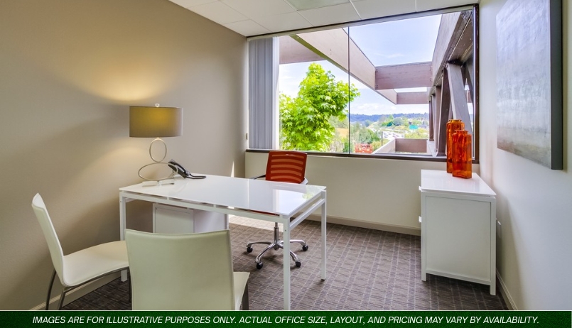 Barrister Suites Office Lease A modern office with two white desks, an orange chair, a white chair, a lamp, and orange decor, featuring a large window with a view of trees and rooftops outside.